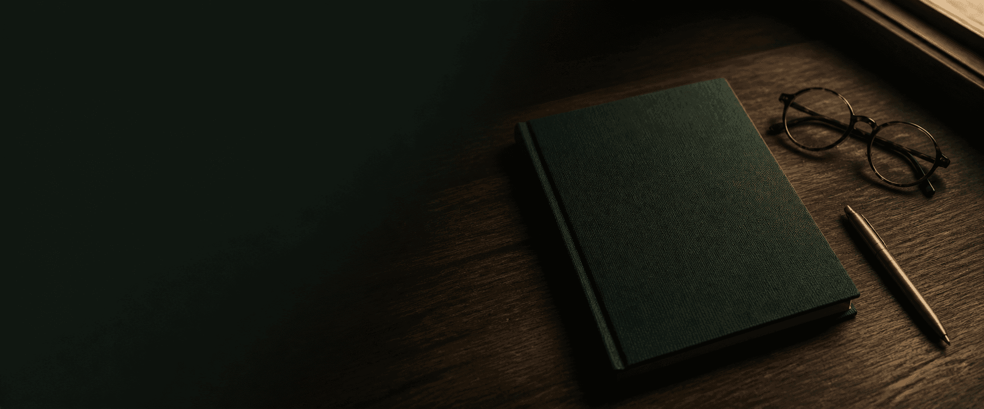 A forest-green guidebook, reading glasses, and brass pen on a dark wood desk